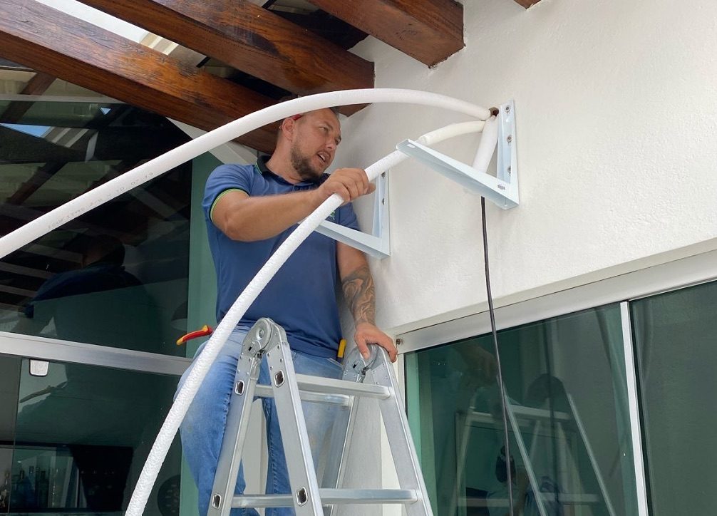 Técnico da Athos instalando a tubulação de um ar-condicionado na parede externa de uma casa